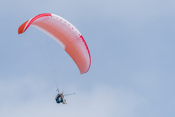 A red and white paraglider flies in the sky