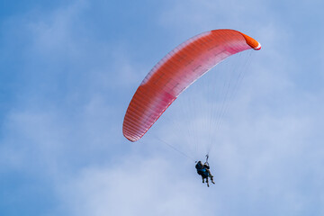 A red and white paraglider flies in the sky