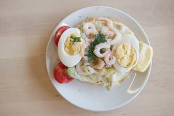 Enjoy a Delicious and Flavorful Seafood Open Sandwich topped with Eggs and Fresh Vegetables