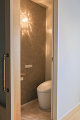 ゆらぎ照明とグレージュ壁紙があるトイレ