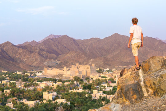 Man standing on a rock, looking at the city and the fortress, Bahla, Oman