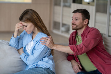 Offended woman turned back from man. Smiling husband touching wife shoulder wanting to apologize,...
