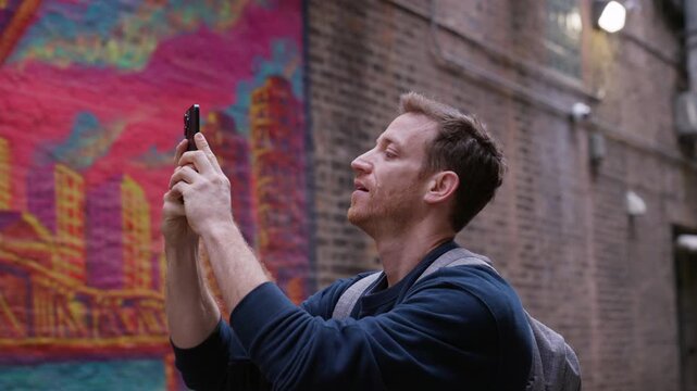 Guy taking pics of graffiti. Tourist exploring Manhattan, capturing the bustling cityscape with his camera. Walks around city, taking pictures and shooting videos of street art. document surroundings.