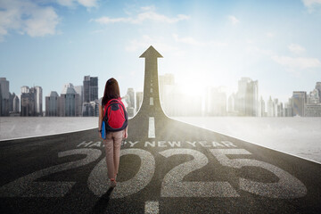 Female college student walking on the road while carrying bag with new year numbers 2025