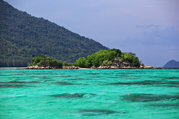 Obraz premium Scenic view white sand beach and crystal Andaman Sea against blue sky at Koh Lipe in Satun Province, Thailand 