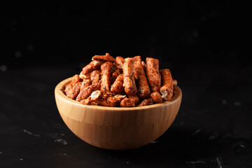 A bowl of Basreng (fried meatballs), a popular Indonesian snack made from thinly sliced fish meatballs, fried until crispy, and coated with spicy seasoning. Photographed against a dark background.