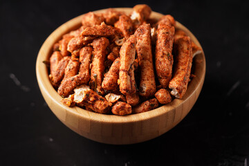 A bowl of Basreng (fried meatballs), a popular Indonesian snack made from thinly sliced fish meatballs, fried until crispy, and coated with spicy seasoning. Photographed against a dark background.