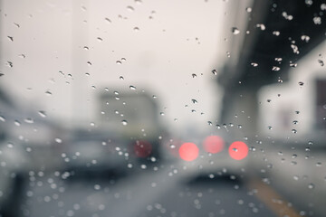 Rain drops on car window and lights. the bokeh image made with traffic and electric lights through the window of car on a rainy day.