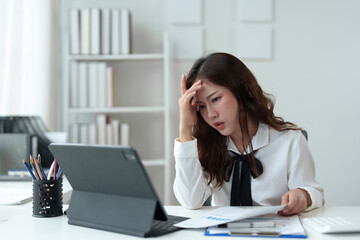 Tired businesswoman having a headache in modern office Creative woman working at office desk Casual female office worker Feeling a headache while working hard on a laptop computer.