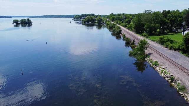 Pewaukee Lake In Waukesha County, Wisconsin, USA. Aerial Drone Flying Parallel To Train Tracks Along The Rising Shoreline.