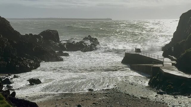 Silvery storm waves crash onto rocks at swimming cove near Tramore IRL