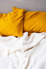 Cozy bed with yellow pillows and white blanket in modern bedroom.