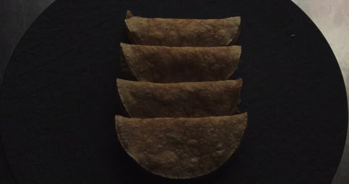 Beautiful shot of a group of 4 chicken tacos or tortillas, a famous Mexican dish cooked in an industrial kitchen in a restaurant.