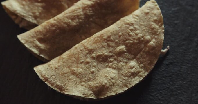 Beautiful slow motion close-up shot of a group of chicken tacos and chilaquies presented on a black plate in an industrial kitchen of a Mexican restaurant.