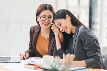 Two businesswomen sharing joyful and supportive moment at the office.