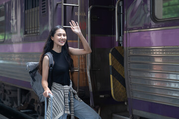 young woman is walking with suitcase at railway station, using the smartphone and map, traveling by train.