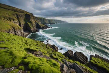 Fototapeta premium Sea flowing near rough rocky cliffs with uneven surface covered with green moss in coastal area of nature against cloudy sky