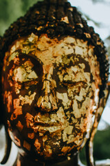 Close up of Buddha head filled with gold leaf. The faces of Buddha statues are venerated by being covered in gold leaf. 