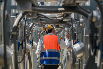 Engineers inspect gas and water pipes for power and cooling in industrial and building systems. workers in safety gear work seriously in oil and gas refining plant with pipes connecting to machinery.