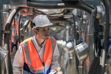 Engineers inspect gas and water pipes for power and cooling in industrial and building systems. workers in safety gear work seriously in oil and gas refining plant with pipes connecting to machinery.