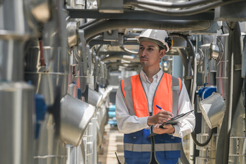 Engineers inspect gas and water pipes for power and cooling in industrial and building systems. workers in safety gear work seriously in oil and gas refining plant with pipes connecting to machinery.