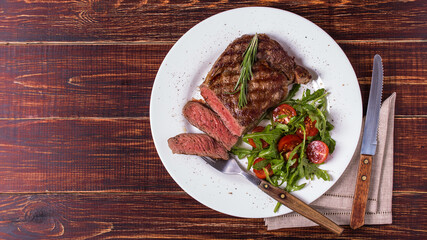 Ribeye steak with arugula and tomatoes.