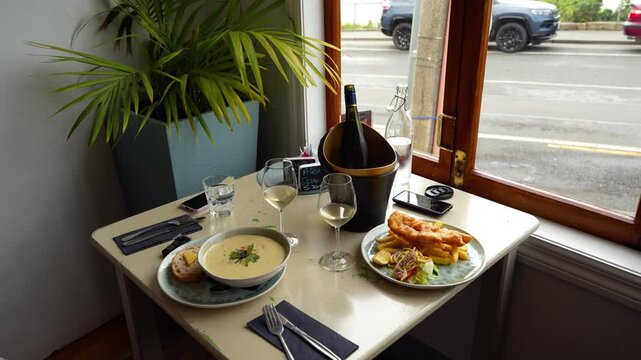 Romantic table setting for two with Fish and Chips and Seafood Chowder in a restaurant.