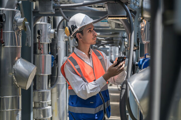 Engineers inspect gas and water pipes for power and cooling in industrial and building systems. workers in safety gear work seriously in oil and gas refining plant with pipes connecting to machinery.