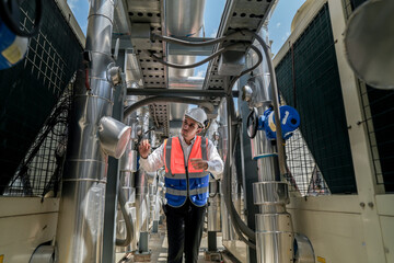 Engineers inspect gas and water pipes for power and cooling in industrial and building systems. workers in safety gear work seriously in oil and gas refining plant with pipes connecting to machinery.