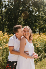 Young couple embracing and smiling in front of wildflowers