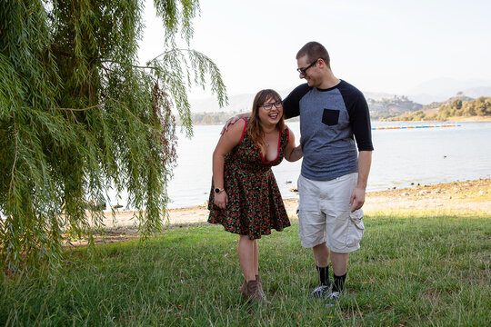 Couple laughing together under a tree by the lakeside