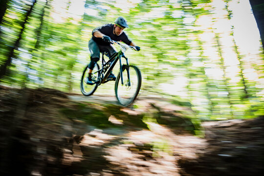 Mountain biker racing downhill through the forest