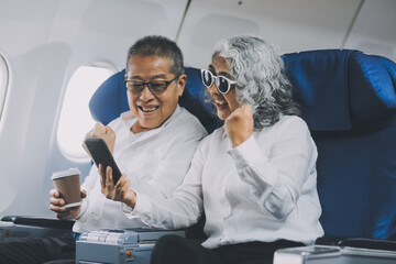 Happy elderly senior couple of travelers with suitcase in airport