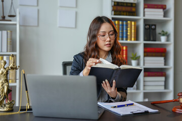 A bespectacled lawyer or legal consultant working at the level of justice sits at a table and holds a pen to view information. Detailed content about jurisprudence to study in the field of law.