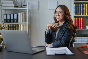A bespectacled lawyer or legal consultant working at the level of justice sits at a table and holds a pen to view information. Detailed content about jurisprudence to study in the field of law.
