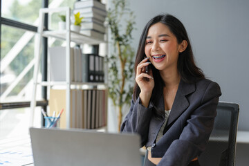 Young Asian woman doing business talking on smartphone. Female accountant. Independent businessman with data documents at desk. Doing business. Contacting customers online. Startup business idea.