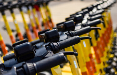A row of electric scooters stands ready for rent, showcasing their vibrant colors. Electric...