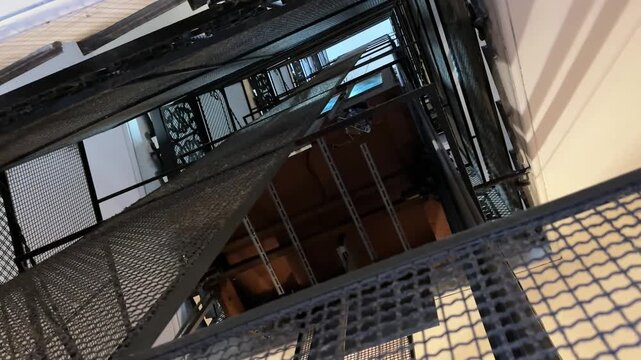 Vintage elevator seen going down from outside metal shaft in retro building
