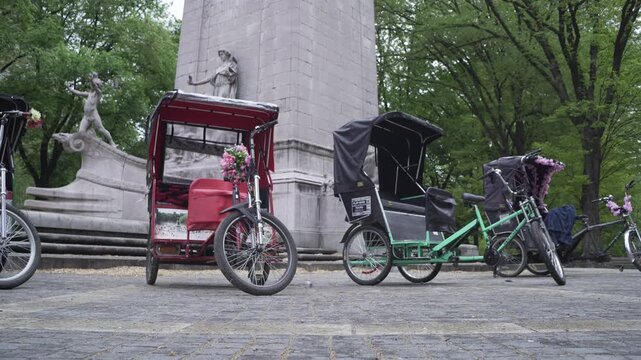 tuk tuk rickshaw parket in Central Park NYC behind a monument with plant tree in background