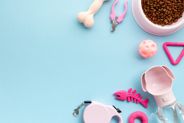 Pet supplies including food bowl, toys, grooming tools, and water bottle against a bright blue background. Flat lay, top view, copy space.