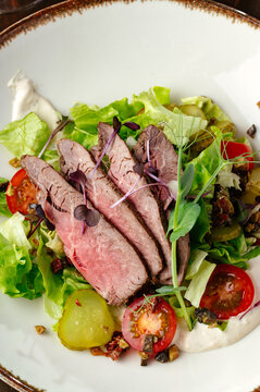 grilled beef tenderloin in a plate with sauce and side dish