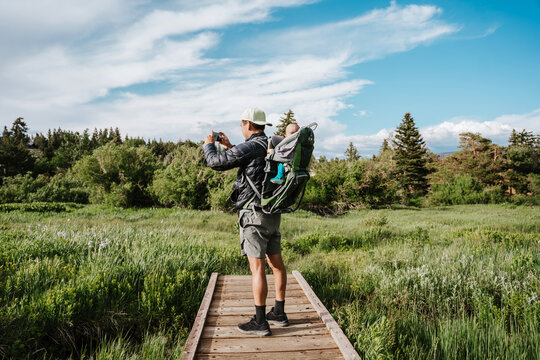 Man taking photo of scenic area with baby in backpack - Powered by Adobe