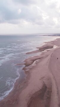 Vertical Aerial view of tropical sandy beach at Mandvi, Kutch, India. Beach waves and clouds in sky during monsoon season. Bird Eye View 4K Cinematic Drone Footage. Travel and holidays concept.