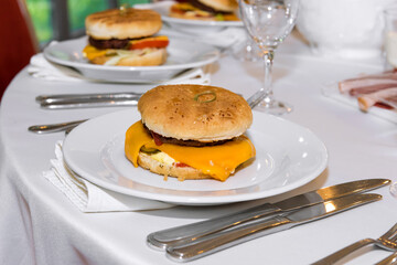 A popular American burger with minced beef, lettuce leaves, tomatoes, cheese, served in a soft bun. Freshly baked sandwich sprinkled with sesame seeds. delicious burger, burger menu, fast food.