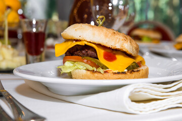 A popular American burger with minced beef, lettuce leaves, tomatoes, cheese, served in a soft bun. Freshly baked sandwich sprinkled with sesame seeds. delicious burger, burger menu, fast food.