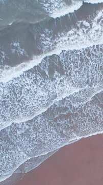 Vertical aerial view of calm ocean waves and sandy beach in Mandvi, Kutch, India. Top down view over ocean coast. Serene and Tranquil Landscape of beach. Drone moving downwards