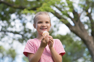 smiling child girl eats ice cream in nature in summer 