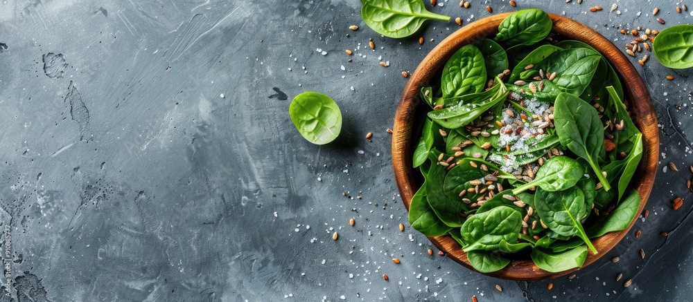 Poster a wooden bowl filled with fresh spinach leaves sea salt and a mixture of seeds and nuts forming a wh