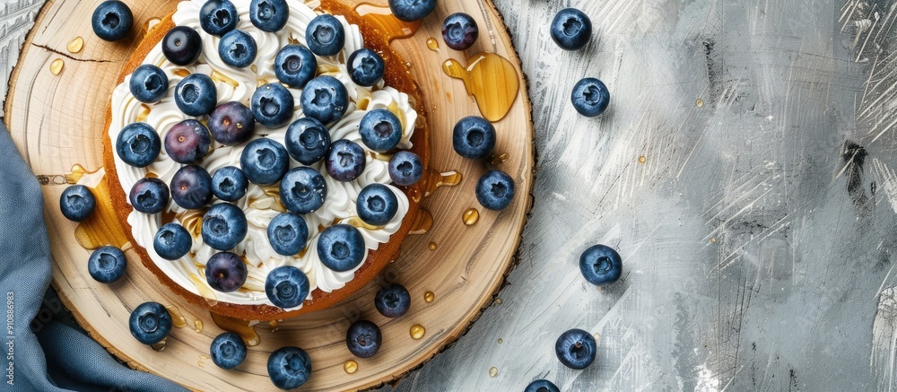 Poster top view of a sweet honey cake on a cutting board decorated with blueberries set against a concrete 