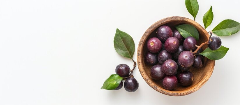 Ripe phalsa fruit in a wooden bowl with leaves isolated on a white background emphasizing a top view with selective focus and copy space image